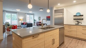A modern kitchen with a central island, stainless steel appliances, and wooden cabinetry. - Suite 203- Spacious two Bedroom apartment-style Suite in Hybrid Hotel Wolfville (Wolfville)