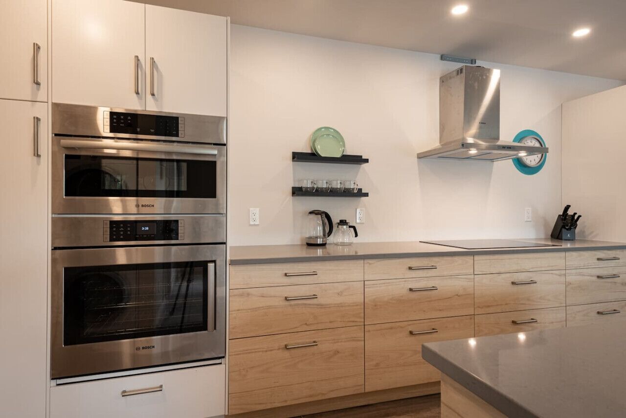 A modern kitchen with stainless steel appliances, wooden cabinets, and a built-in oven.