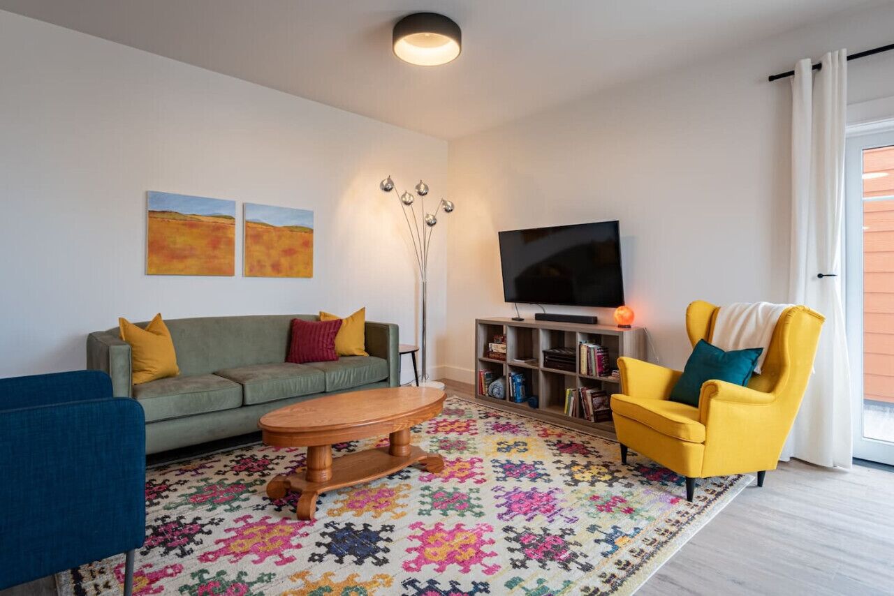 A living room with a sofa, armchair, coffee table, and a TV.