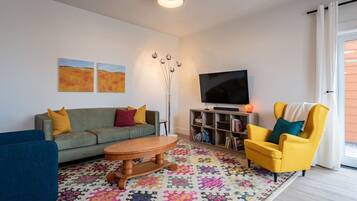 A living room with a sofa, armchair, coffee table, and a TV.