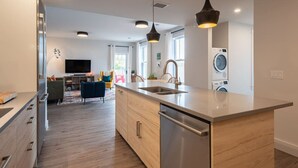 A modern kitchen with a central island, built-in appliances, and pendant lighting. - Suite 302 - 470 Main (Wolfville)