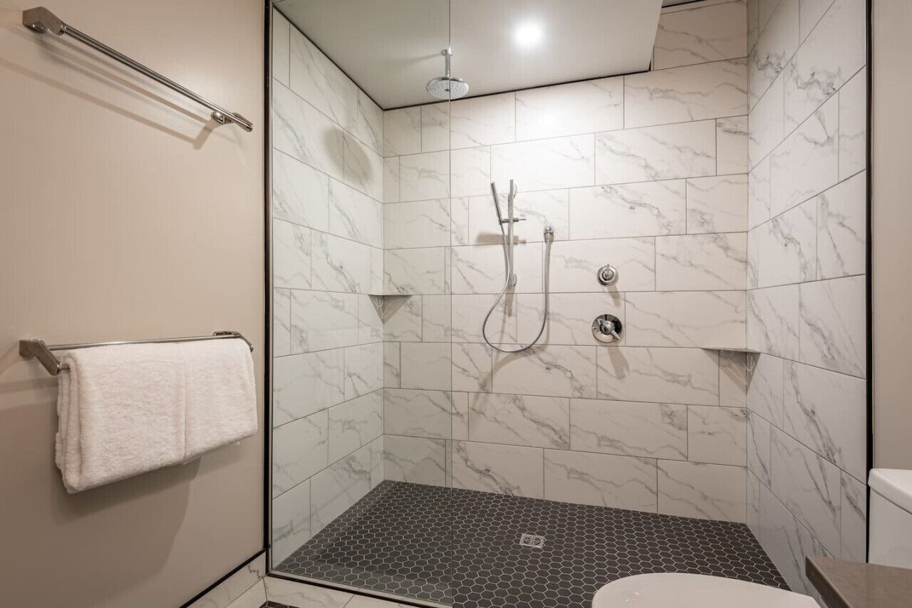 A shower with a glass door, a towel rack, and a toilet.