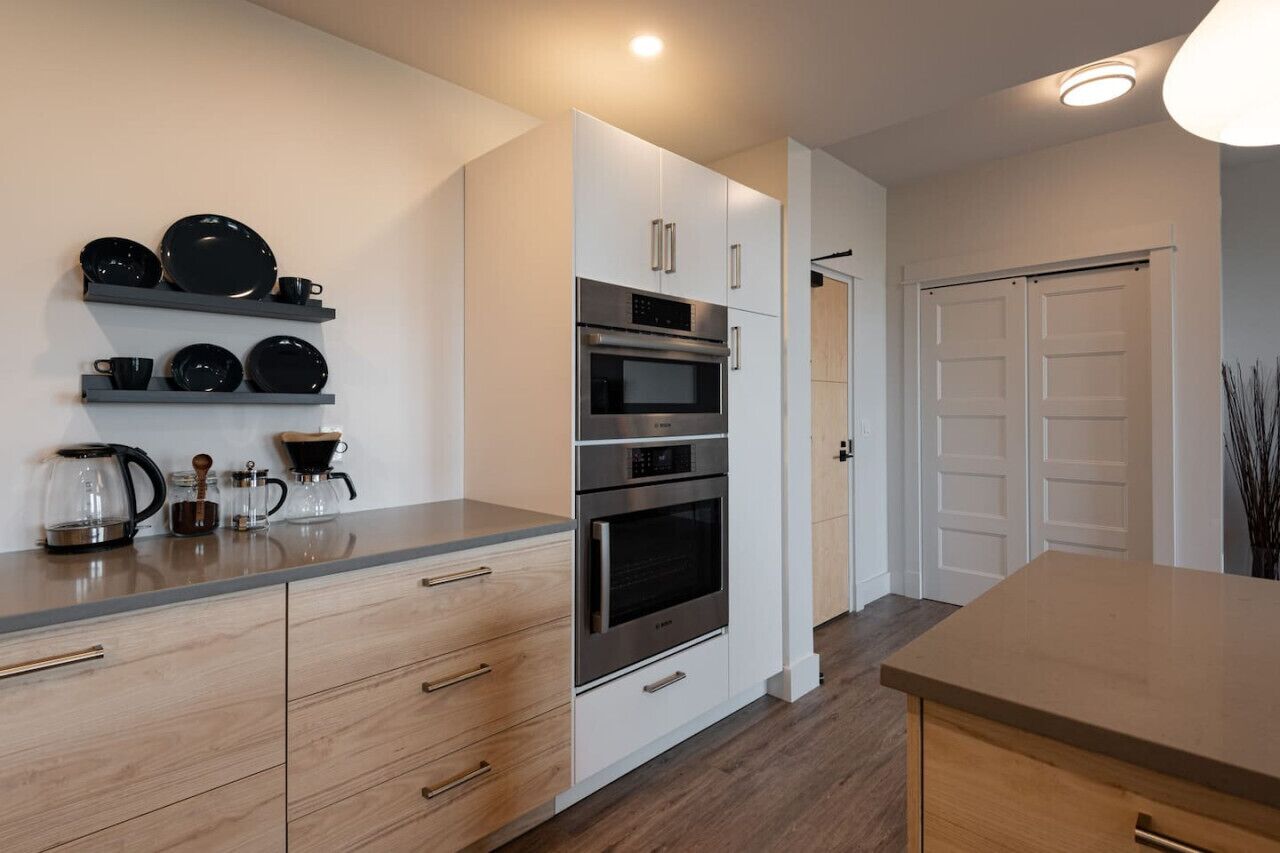 Une cuisine moderne avec des meubles blancs, des appareils en acier inoxydable et une machine à café posée sur le plan de travail.