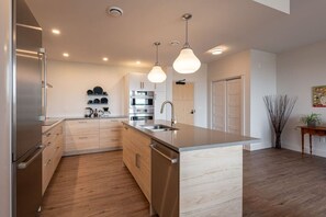 A modern kitchen with stainless steel appliances, wooden cabinets, and pendant lighting. - Suite 304- Two Bedroom apartment-style Suite w Balcony in Hybrid Hotel Wolfville (Wolfville)