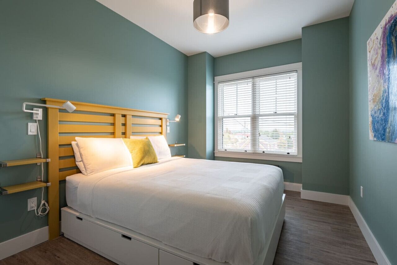 Une chambre à coucher avec un lit, des tables de chevet, une fenêtre et un tableau au mur.
