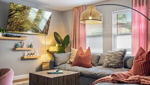 A modern living room with a grey sofa, a wooden coffee table, and a large painting on the wall. - Hot Tub - Family - Dogs Allowed - Arcade Machine -MegaChess STR-A-25-00194 (St. Petersburg)