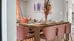 A dining area with a wooden table set for four, pink chairs, and a vase with dried plants. - Hot Tub - Family - Dogs Allowed - Arcade Machine -MegaChess STR-A-25-00194 (St. Petersburg)