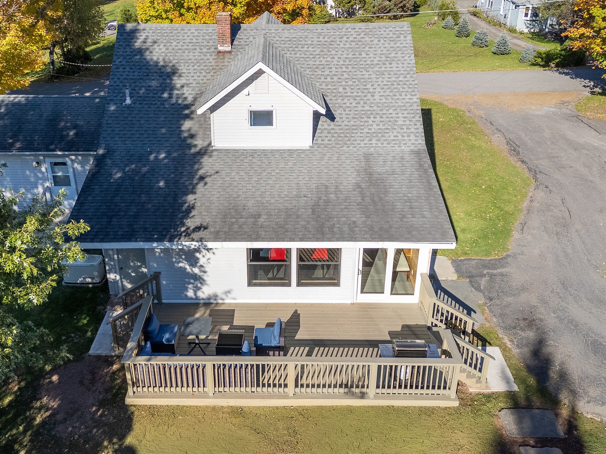 A two-story house with a covered deck and outdoor seating.