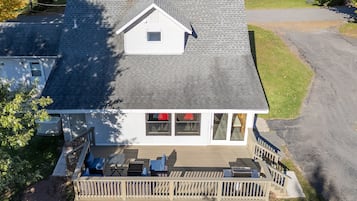 A two-story house with a covered deck and outdoor seating.