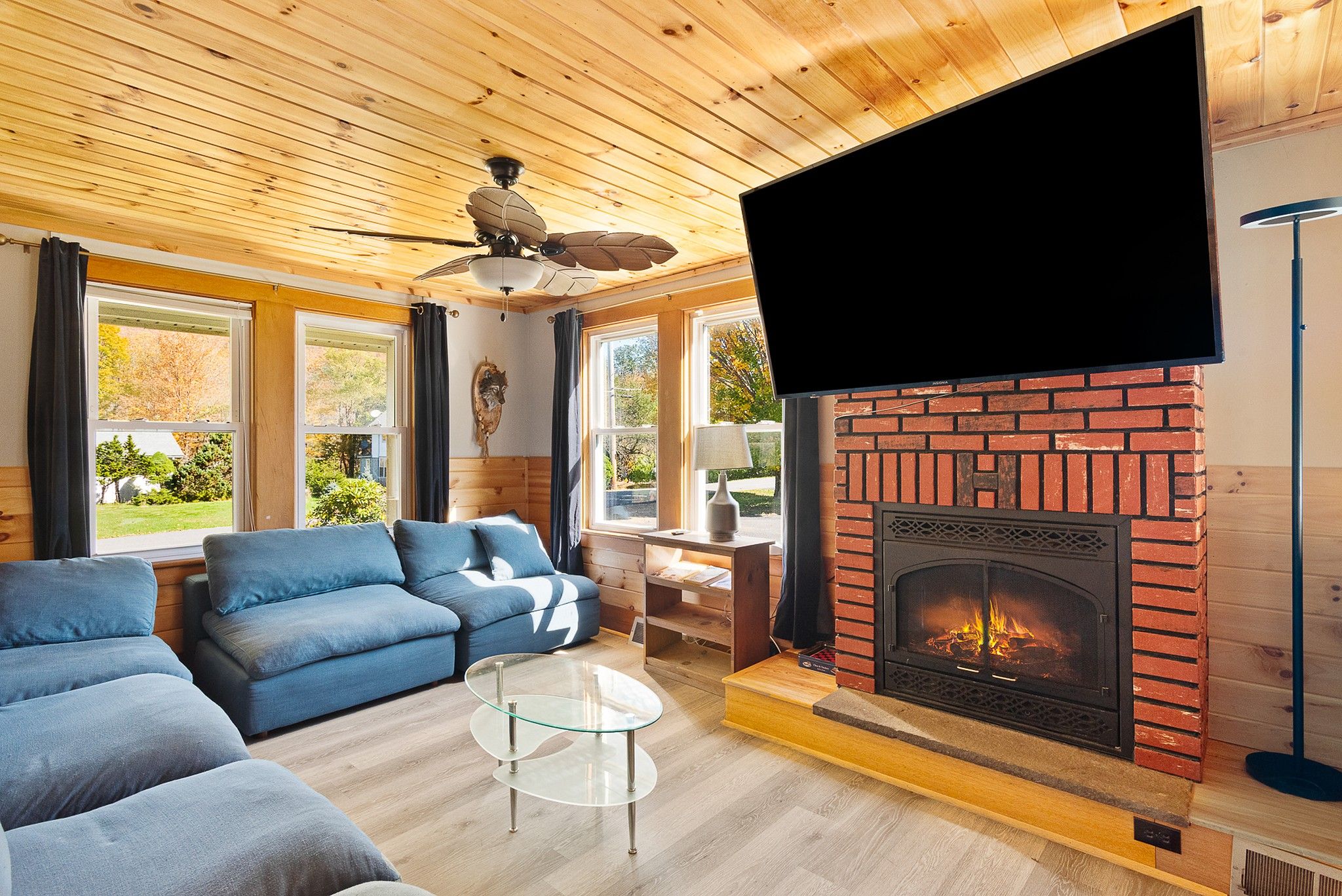 A cozy living room with a fireplace, blue sofas, and a flat-screen TV.