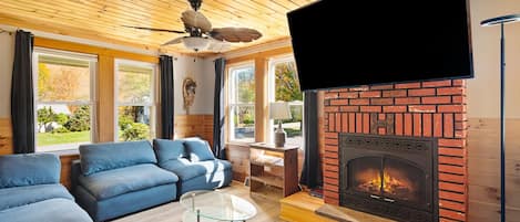 A cozy living room with a fireplace, blue sofas, and a flat-screen TV.