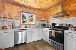 A modern kitchen with white cabinets, stainless steel appliances, and a wooden ceiling. - CHALET with INDOOR POOLHOUSE base of HUNTER mountain (Lanesville)