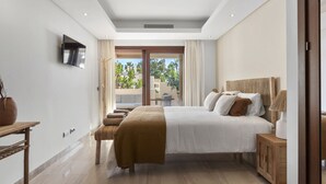 A bedroom with a bed, bedside table, and a TV mounted on the wall. - Penthouse Bahia de la Plata (Estepona)