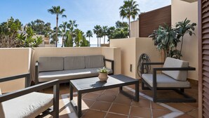 A patio with a sofa, two chairs, a table, and a potted plant. - Penthouse Bahia de la Plata (Estepona)
