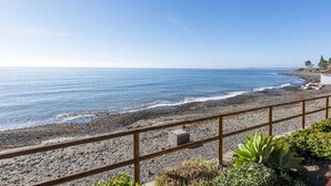 A coastal view with a rocky beach, a wooden railing, and some greenery. - Penthouse Bahia de la Plata (Estepona)