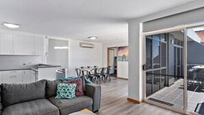 Un appartement moderne doté d’une kitchenette, d’un coin repas et d’un balcon avec mobilier d’extérieur.