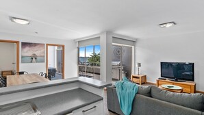 Un appartement moderne comprenant une cuisine, un coin repas et un salon. Il dispose d’un balcon avec vue sur la mer.