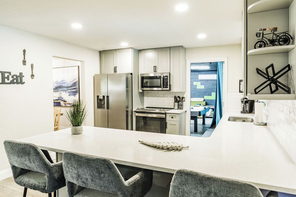 A modern kitchen with white cabinets, stainless steel appliances, and a central island with seating.