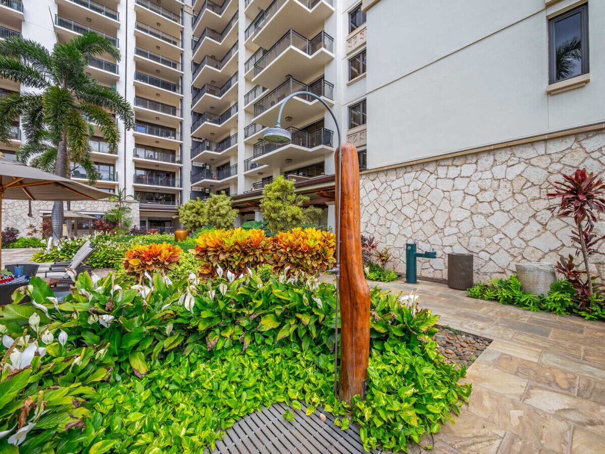 A landscaped outdoor area with a stone wall, a wooden post, and various plants.