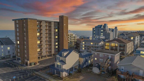 Un quartier résidentiel situé sur la côte, avec des immeubles à plusieurs étages, un parking et une vue sur la mer.