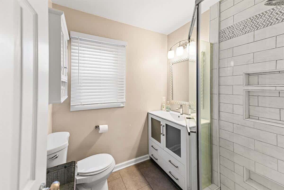A bathroom with a toilet, a vanity with a mirror, and a shower area.