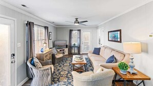 Una sala de estar con sofá, sillón, mesa de centro y televisor.