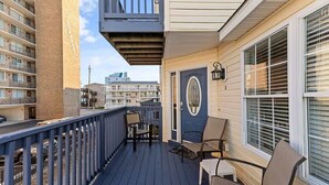 A balcony with outdoor seating, a door with a circular window, and a view of other buildings.
