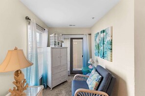 A room with a bed, a chair, a lamp, a cabinet, and a painting on the wall.