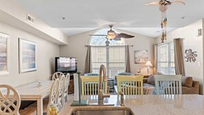 A kitchen with a granite countertop, stainless steel sink, and a ceiling fan.