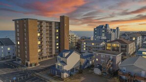 A coastal residential area with multi-story buildings, a parking lot, and a view of the sea.