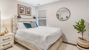 Une chambre à coucher avec un lit, une table de chevet et une plante en pot.