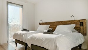 Ein Doppelbett mit weißen Leinen, einem Holzkopfende und einer Nachttischlampe.