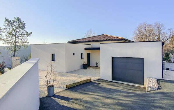 Ett modernt hus med ett garage, en liten uteplats och en grusuppfart.