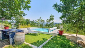 Ein Garten mit Swimmingpool, Grillplatz und Blick auf die umliegende Landschaft.