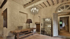 Una habitación rústica con vigas de madera a la vista, un banco de madera, un candelabro y un espejo grande.