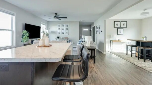 A modern kitchen with a marble countertop, black chairs, and a dining area with a table and chairs. - Modern, Spacious Whole Unit Traveler's Home! (Fort Wayne)