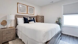A bedroom with a bed, nightstands, a lamp, and framed artwork on the wall. - Modern, Spacious Whole Unit Traveler's Home! (Fort Wayne)