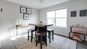 A modern kitchen with a central island, pendant lighting, and a large window providing natural light. - Modern, Spacious Whole Unit Traveler's Home! (Fort Wayne)