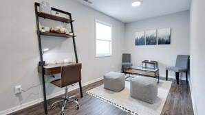 A modern room with a desk, chair, ottoman, and shelving unit. - Modern, Spacious Whole Unit Traveler's Home! (Fort Wayne)