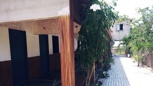 Un'area esterna coperta con un vialetto in mattoni, colonne in legno e un edificio con diverse porte.