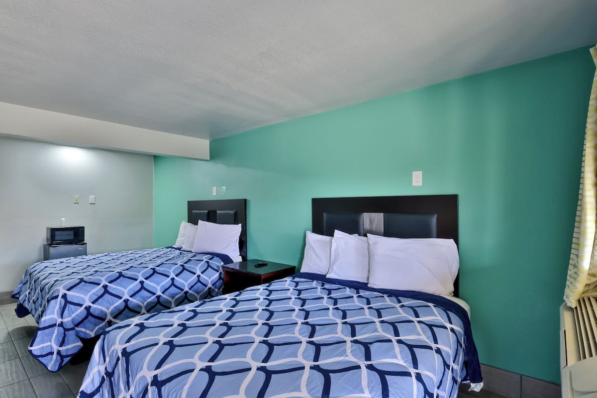 Two single beds with headboards, a small bedside table, and a television on the left.