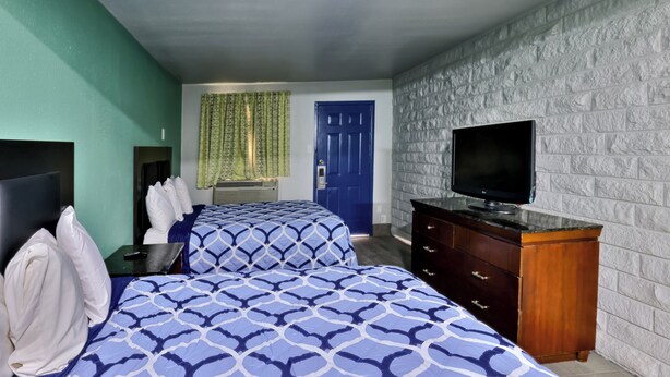 Une chambre d’hôtel avec deux lits, une télévision, une commode et une porte bleue.