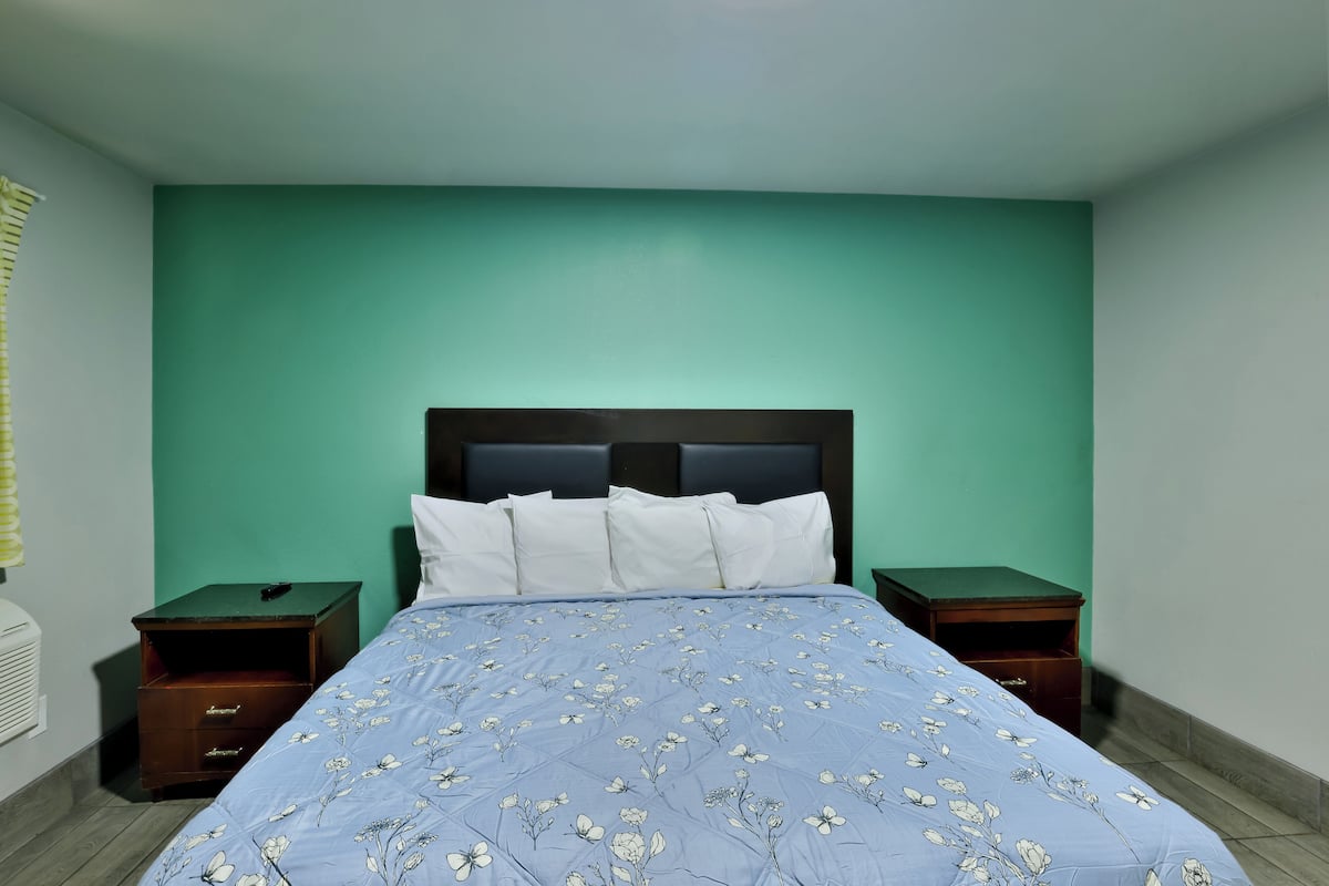 A bedroom with a bed, two nightstands, and a green wall.