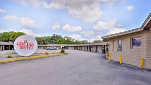 Un motel appelé « El Tejas Motel », avec un ciel dégagé et un parking.