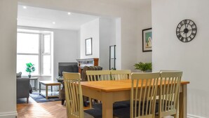 Een eethoek met een houten tafel en stoelen, een televisie en een lijst met een afbeelding aan de muur.