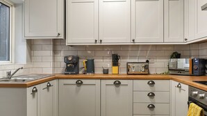 Een keuken met witte kasten, een houten aanrecht, een koffieapparaat, een broodrooster en een magnetron.