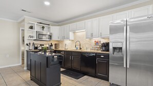 A modern kitchen with white cabinets, stainless steel appliances, and a central island. - Rising Tides Hideaway! (Long Beach)