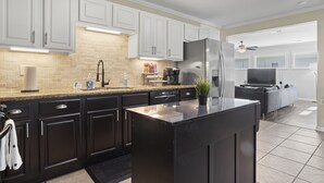 A modern kitchen with dark cabinets, a granite countertop, and a large island. - Rising Tides Hideaway! (Long Beach)