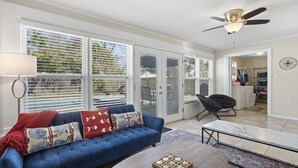 A living room with a blue sofa, a coffee table, and a ceiling fan. - Rising Tides Hideaway! (Long Beach)