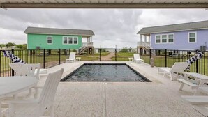 A covered outdoor area with a swimming pool, two houses, and a fence. - Sunset Bay Seagull Cottage (Port Lavaca)
